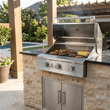 Angled side view of a 5-foot travertine natural stone outdoor kitchen island with an open True Flame gas grill showing food cooking on the grates.